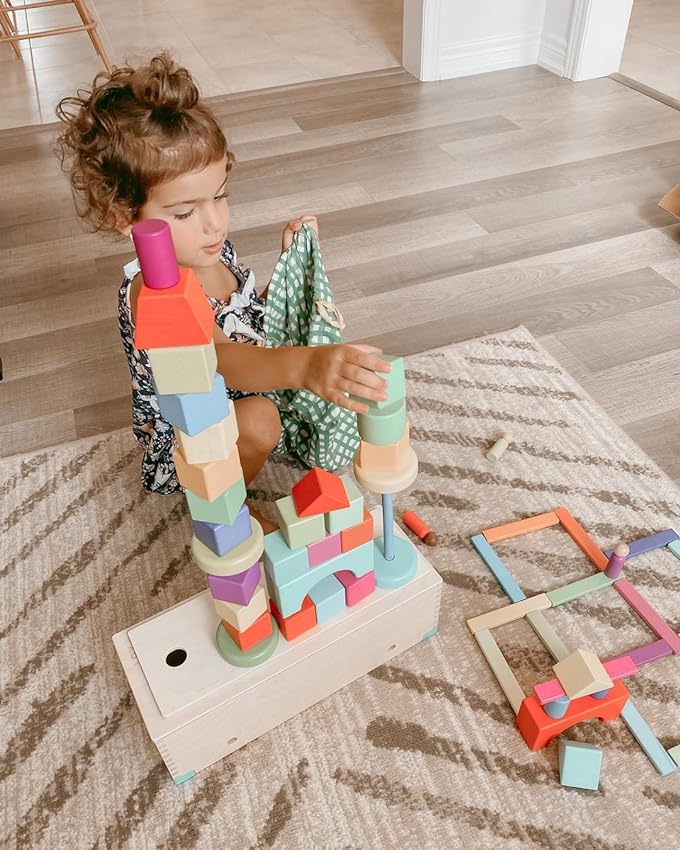 Child building a tower with colorful wooden blocks on a patterned carpet in a living room.